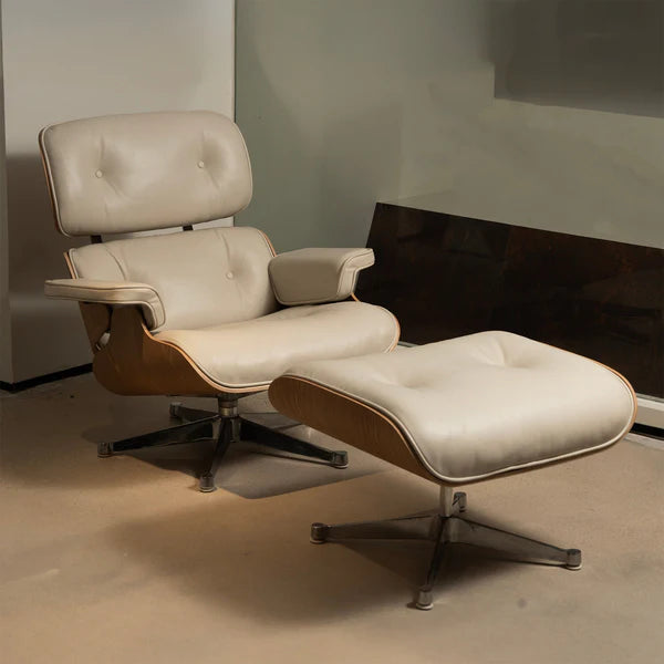 Modern lounge chair with matching ottoman, featuring white leather upholstery, curved wood frame, and a swivel metal base—Eames-inspired design.